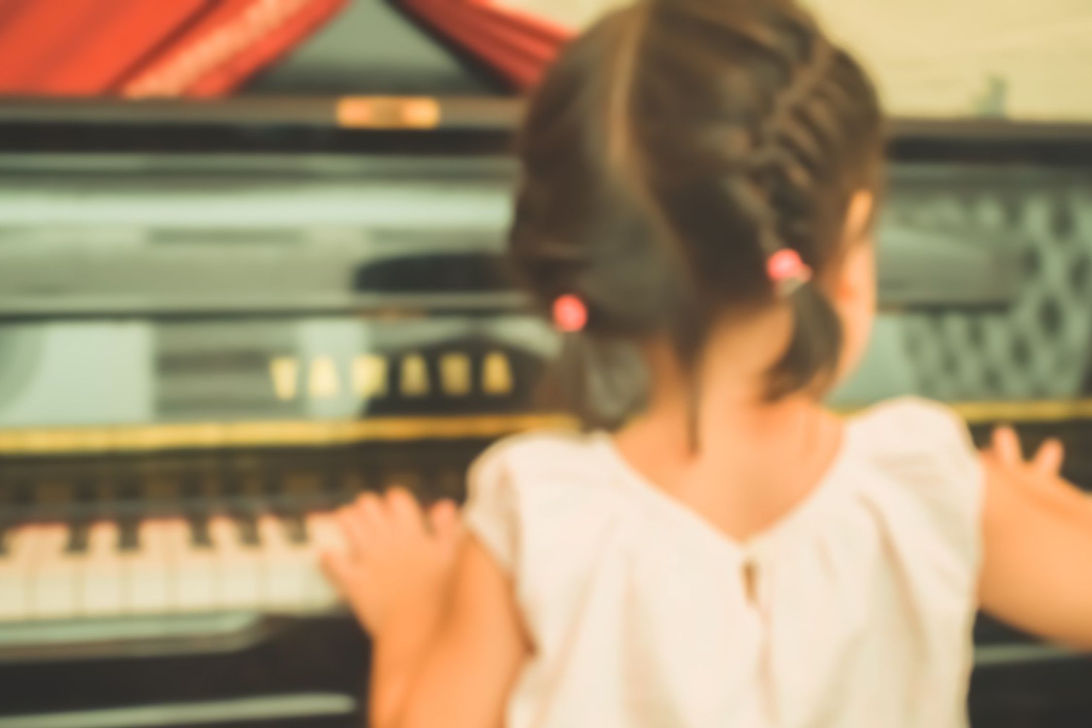 Little girl playing a Yamaha piano.