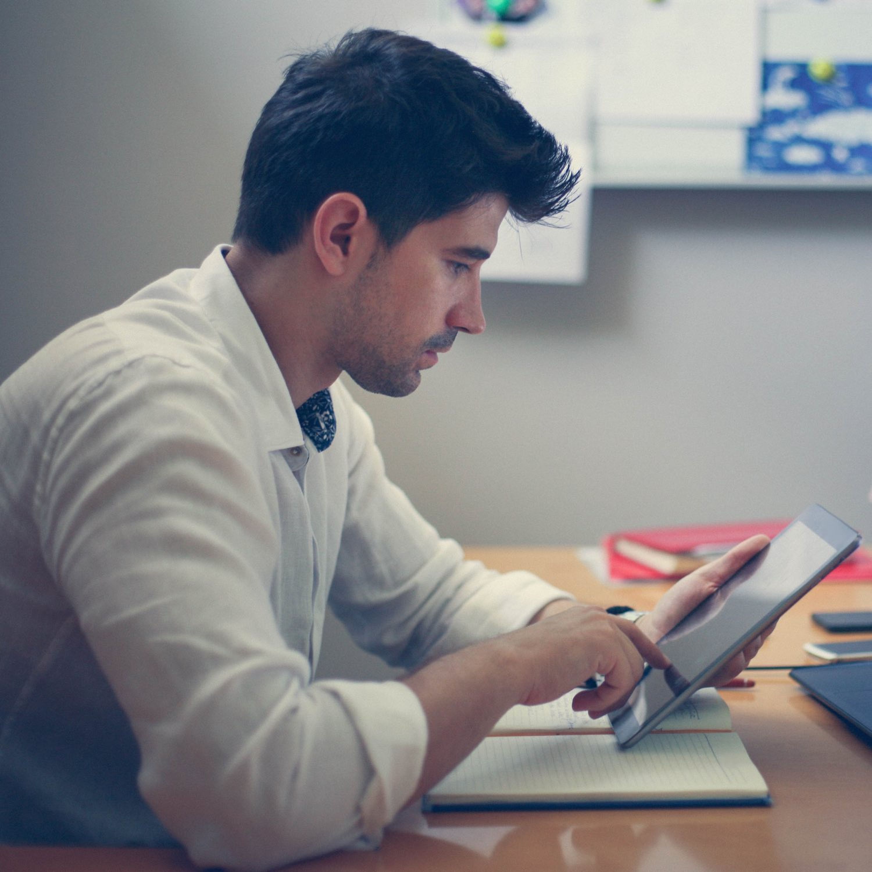 A man sitting at a table looking at an iPad.