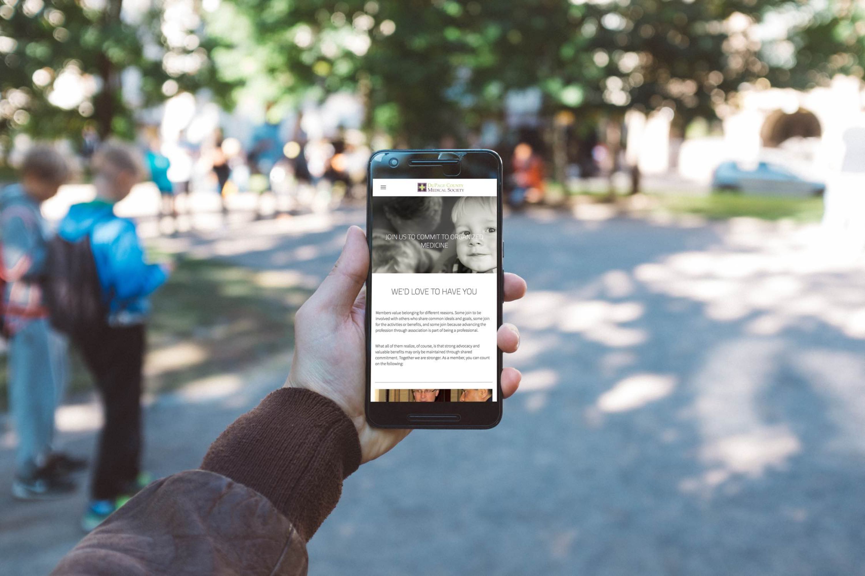 Image of hand holding a phone with image of boy and text.