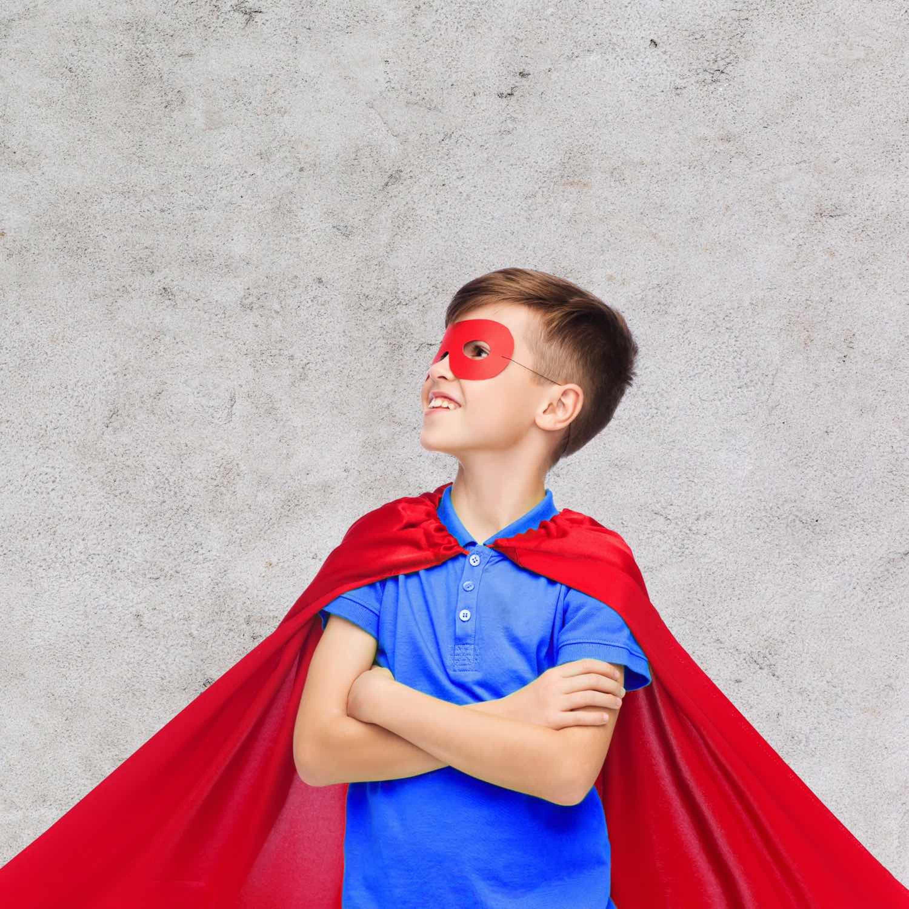 Image of a young boy in a red superhero cape and mask.