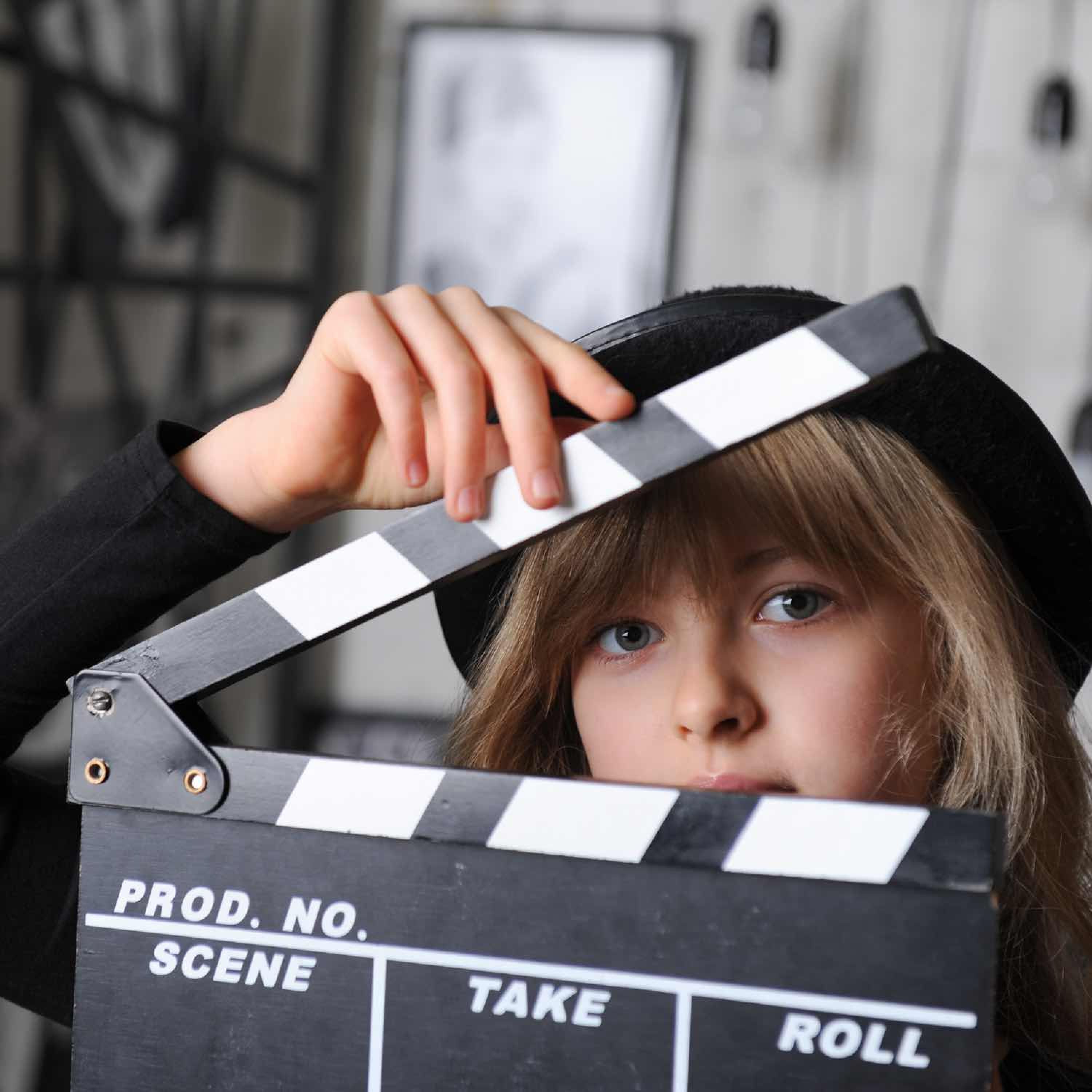 Image of a girl with a movie set click board.