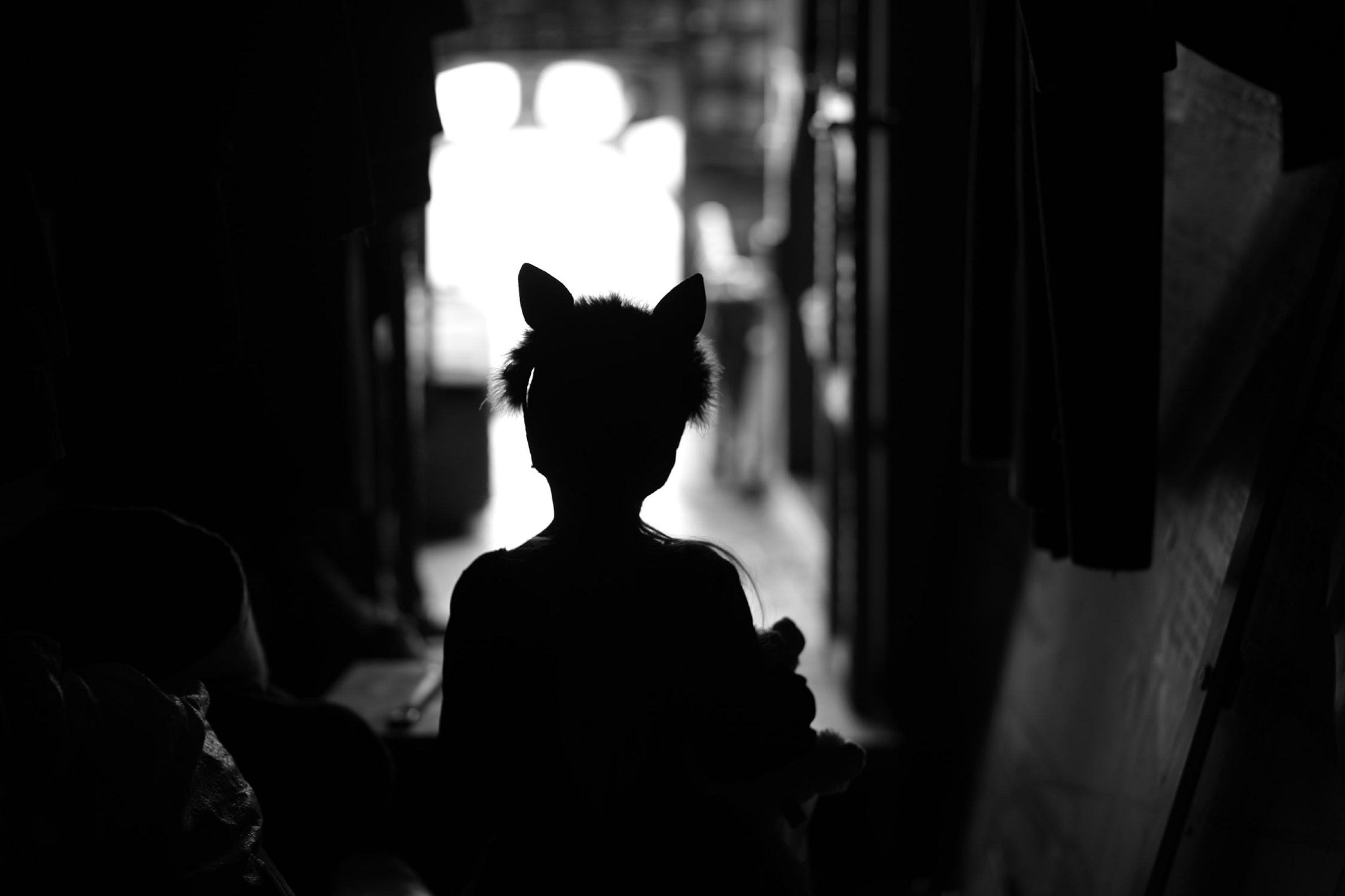 Black and white silhouette of a young child with wearing cat ears on their head.