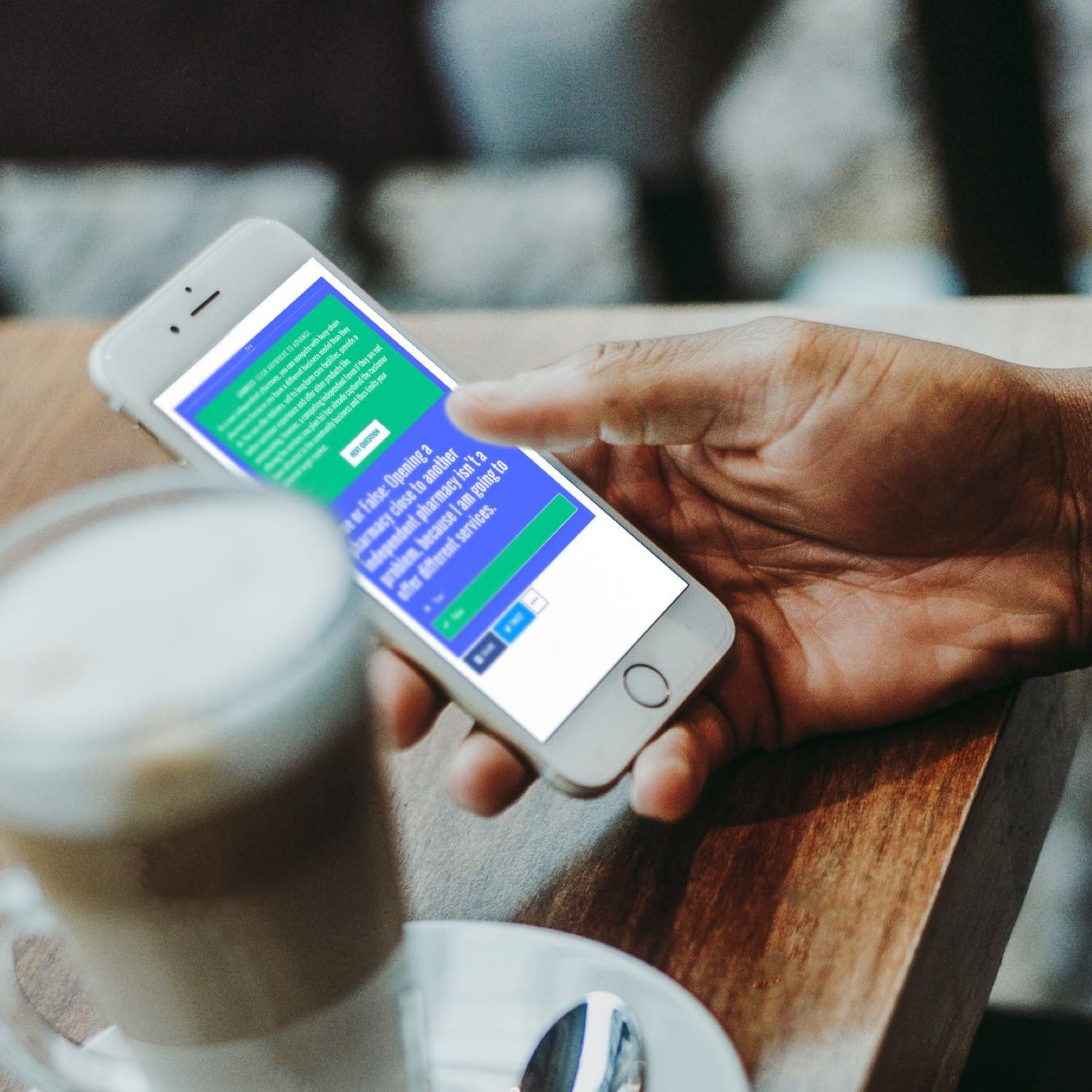 Image of hand holding a phone next to a coffee.