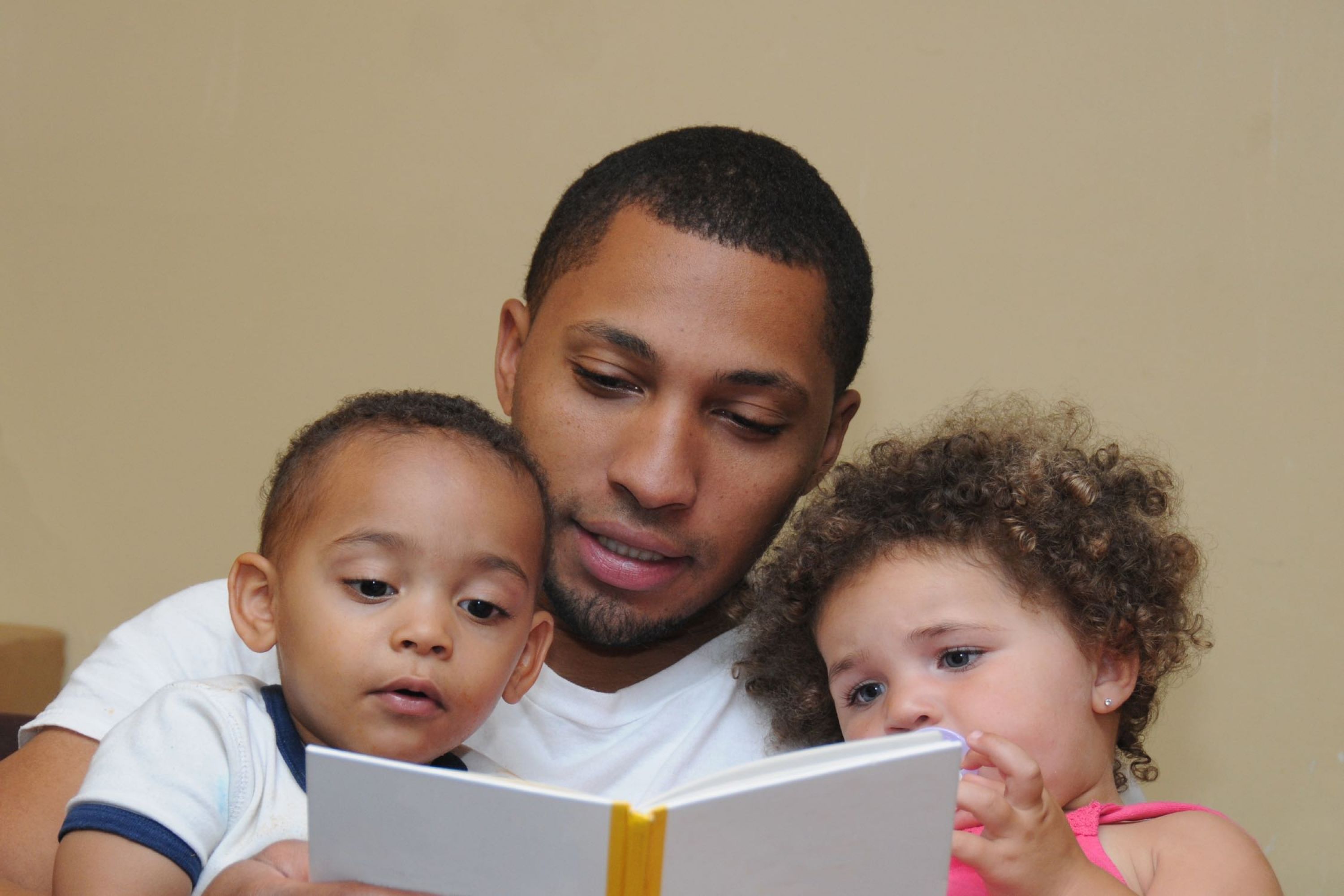 Image of man reading to two children.