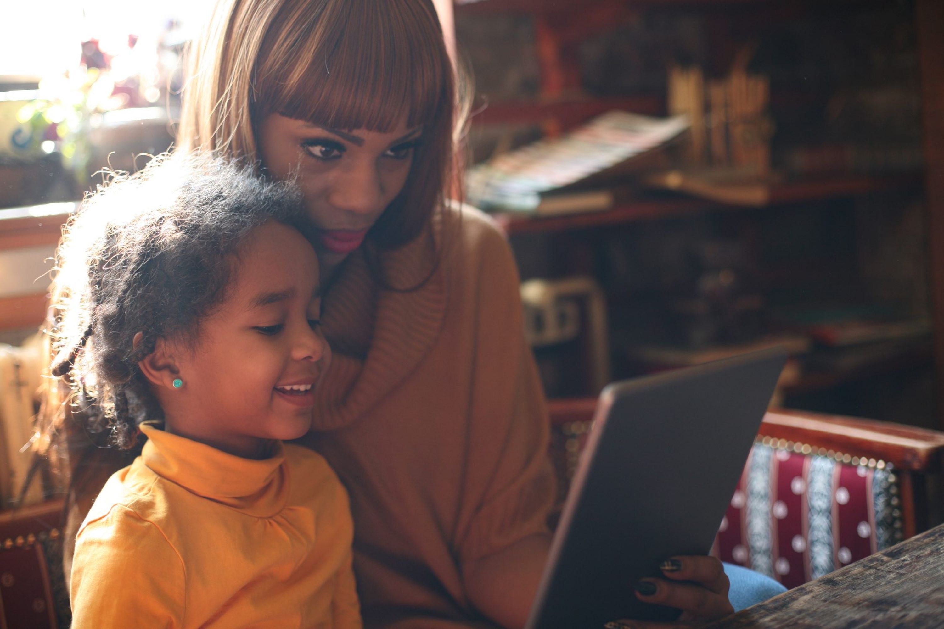 Image of woman reading with a young smiling girl.