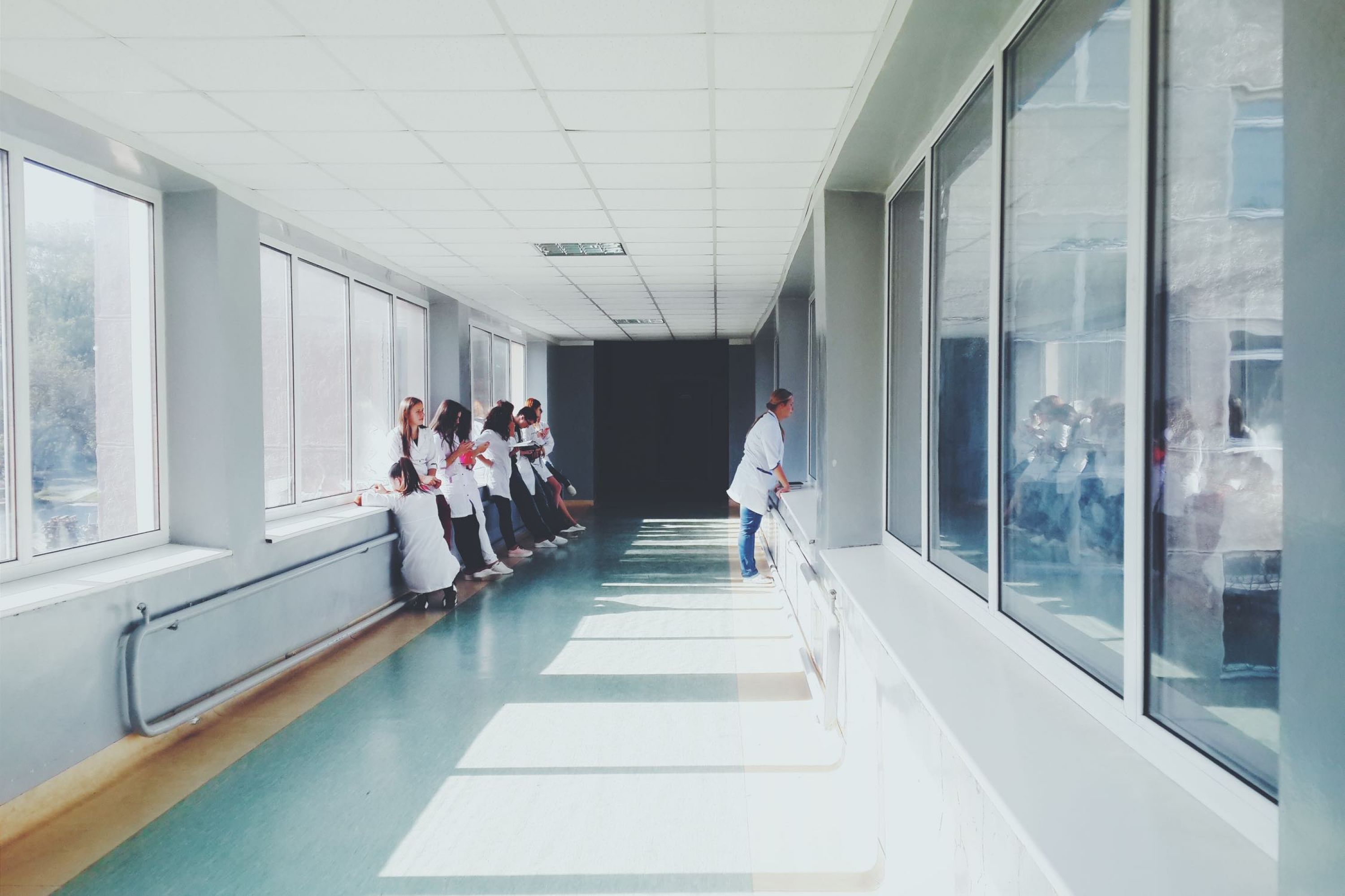 Image of a hospital with people in lab coats lining the hallway.