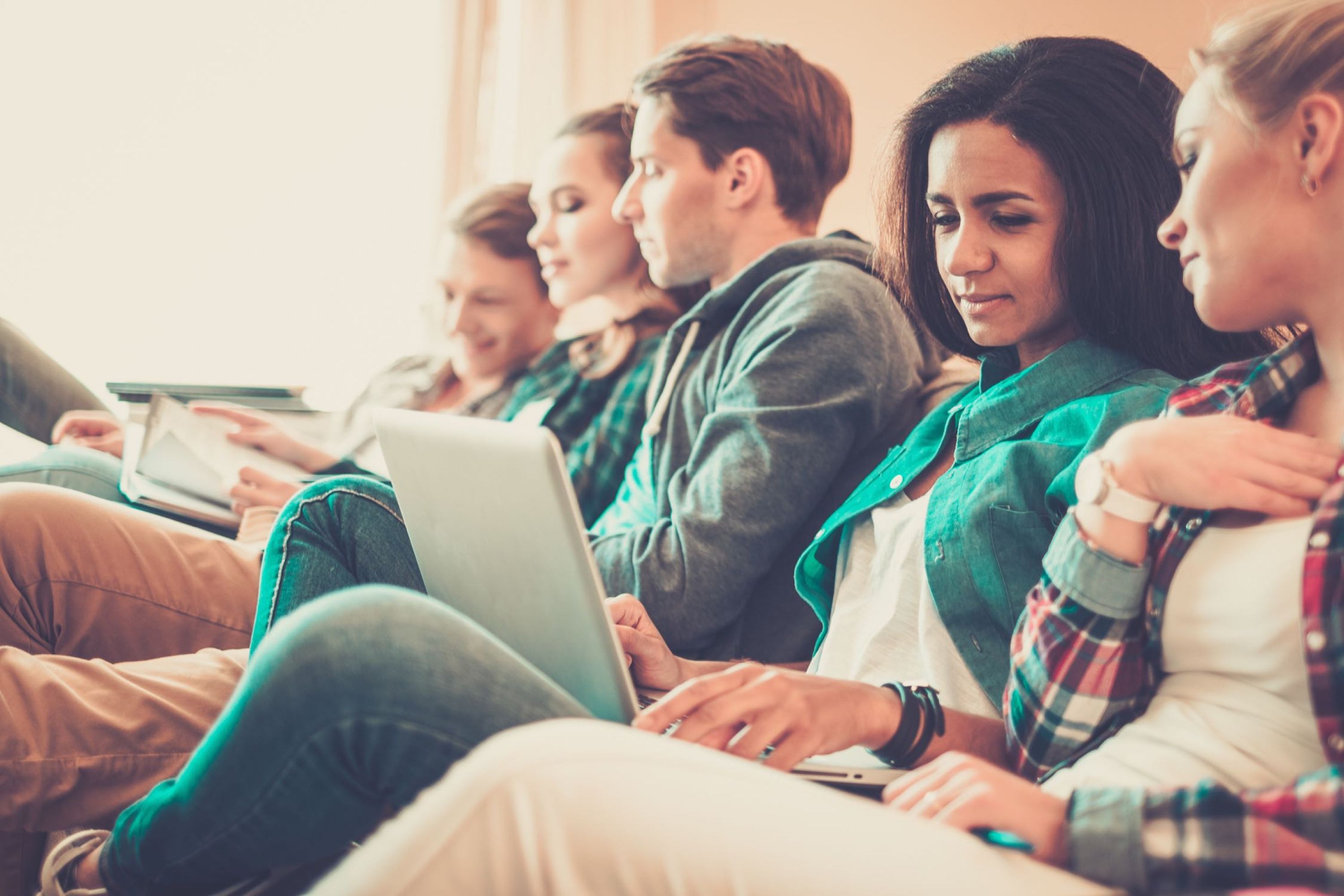 Image of people on a couch looking at laptop.