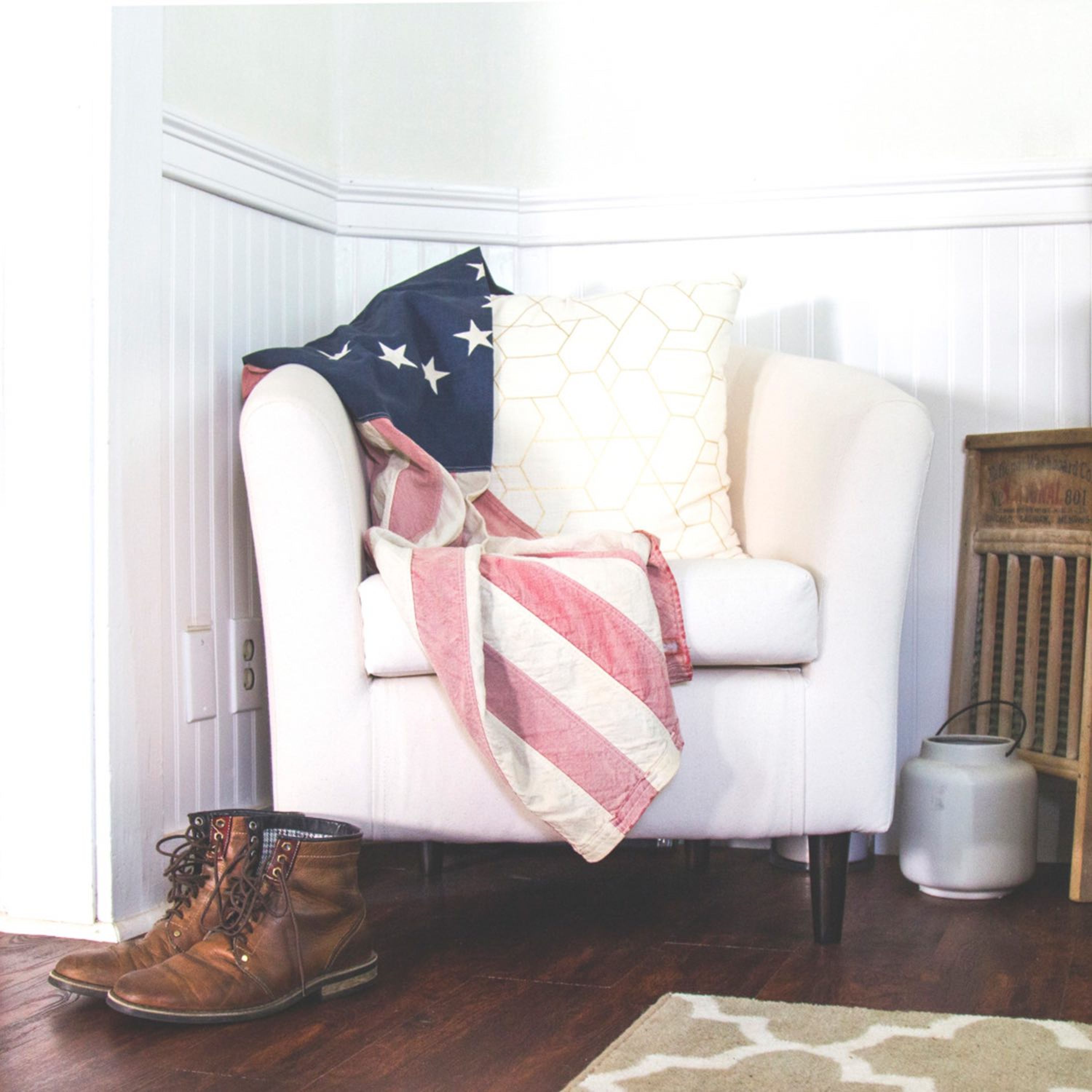 Image of a white lounge chair with American flag draped over it and unlaced work boots on the floor.