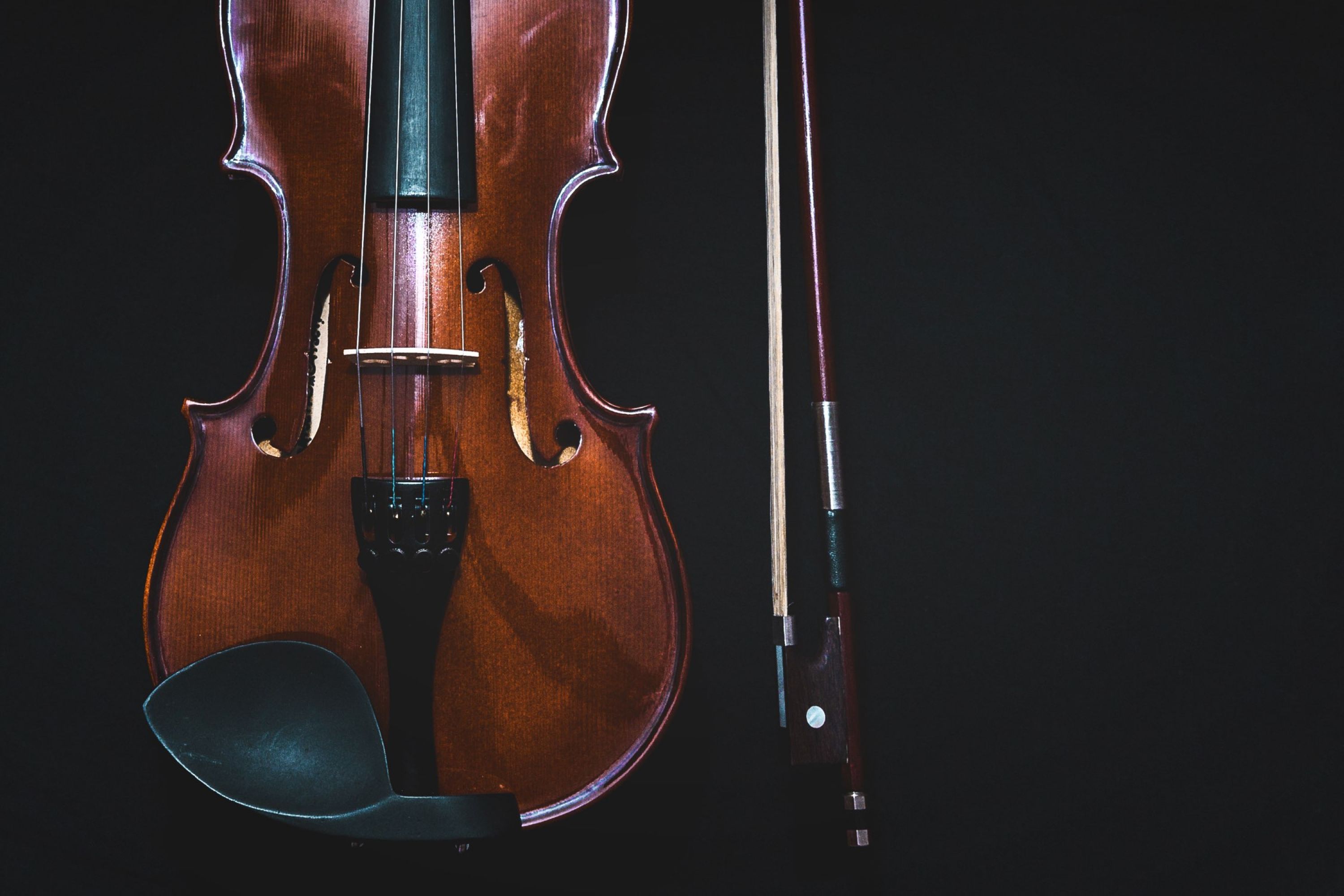 Image of the lower portion of a violin on a black background.