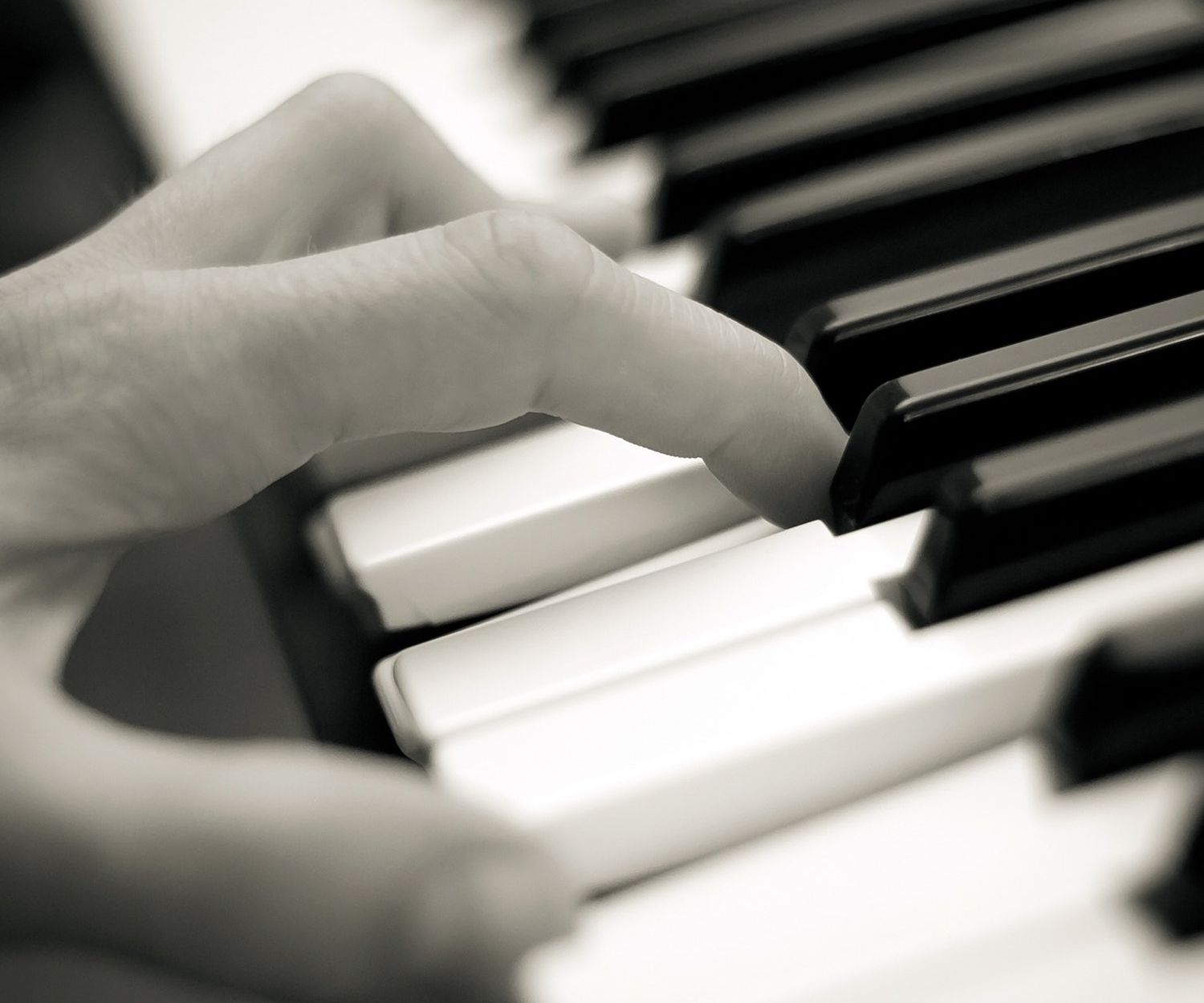 Hand playing keys on a piano.