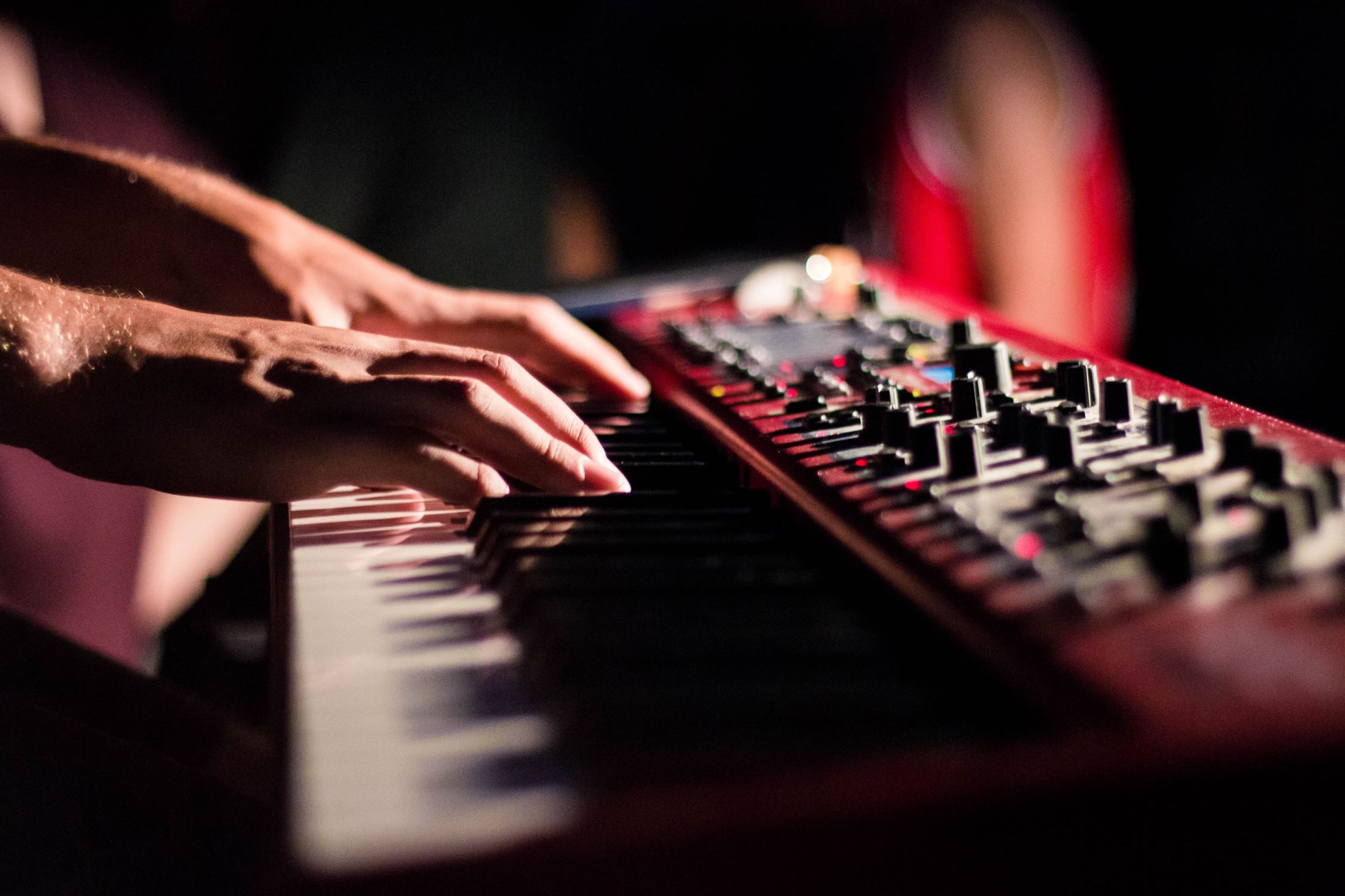 Hands playing a synthesizer.