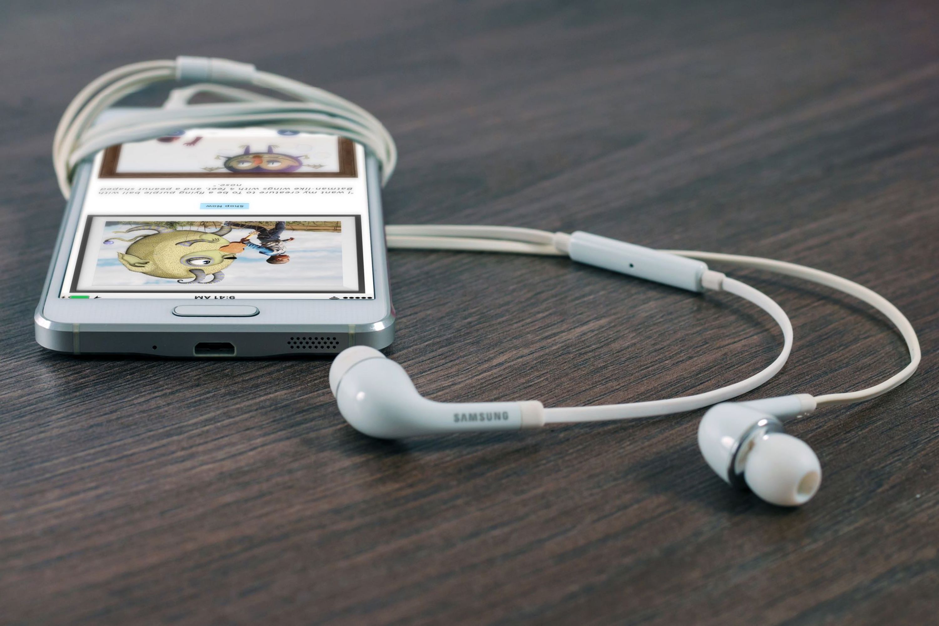 Image of a phone with headphones laying on a table.