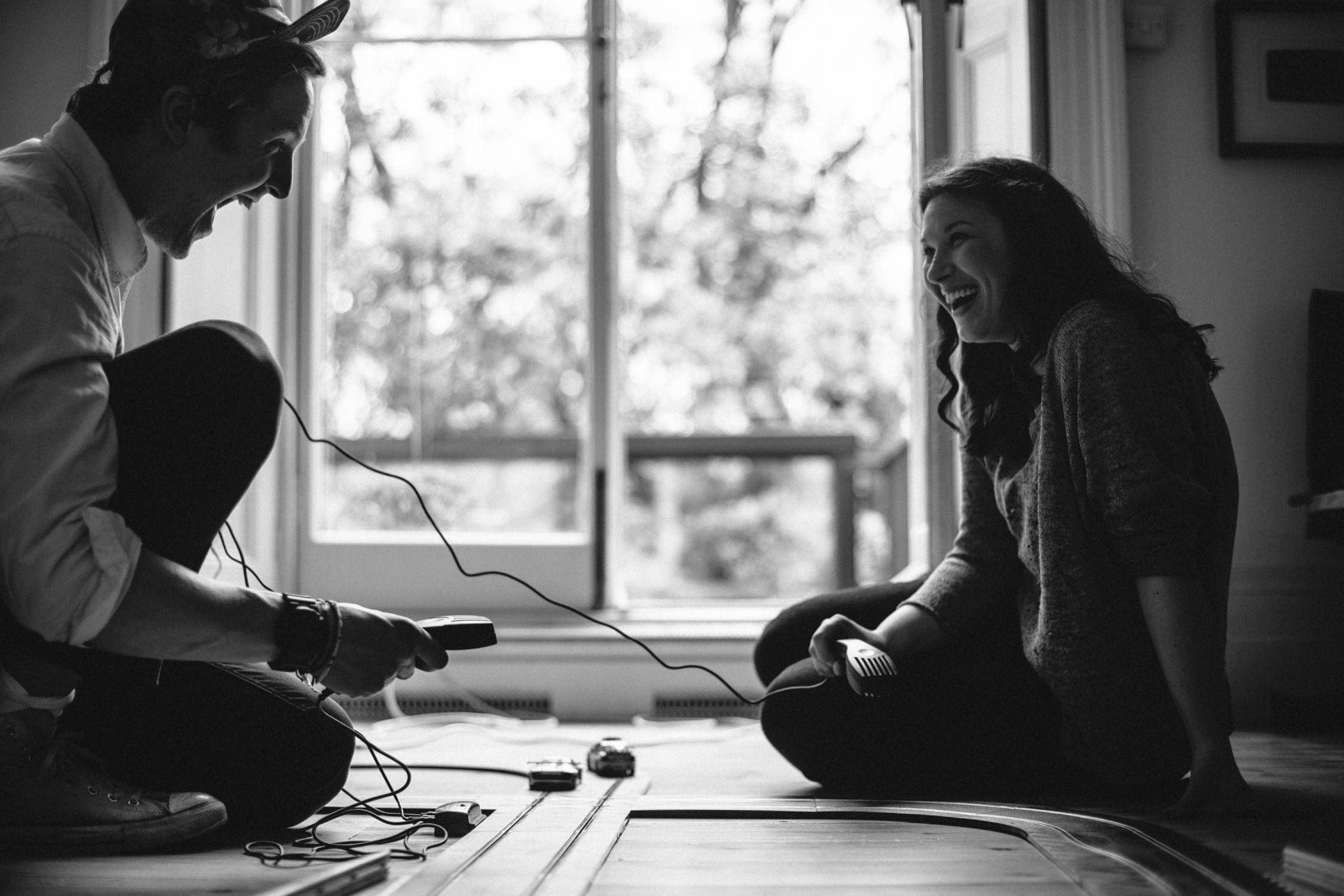 Image of a man and woman playing with a toy race car track.