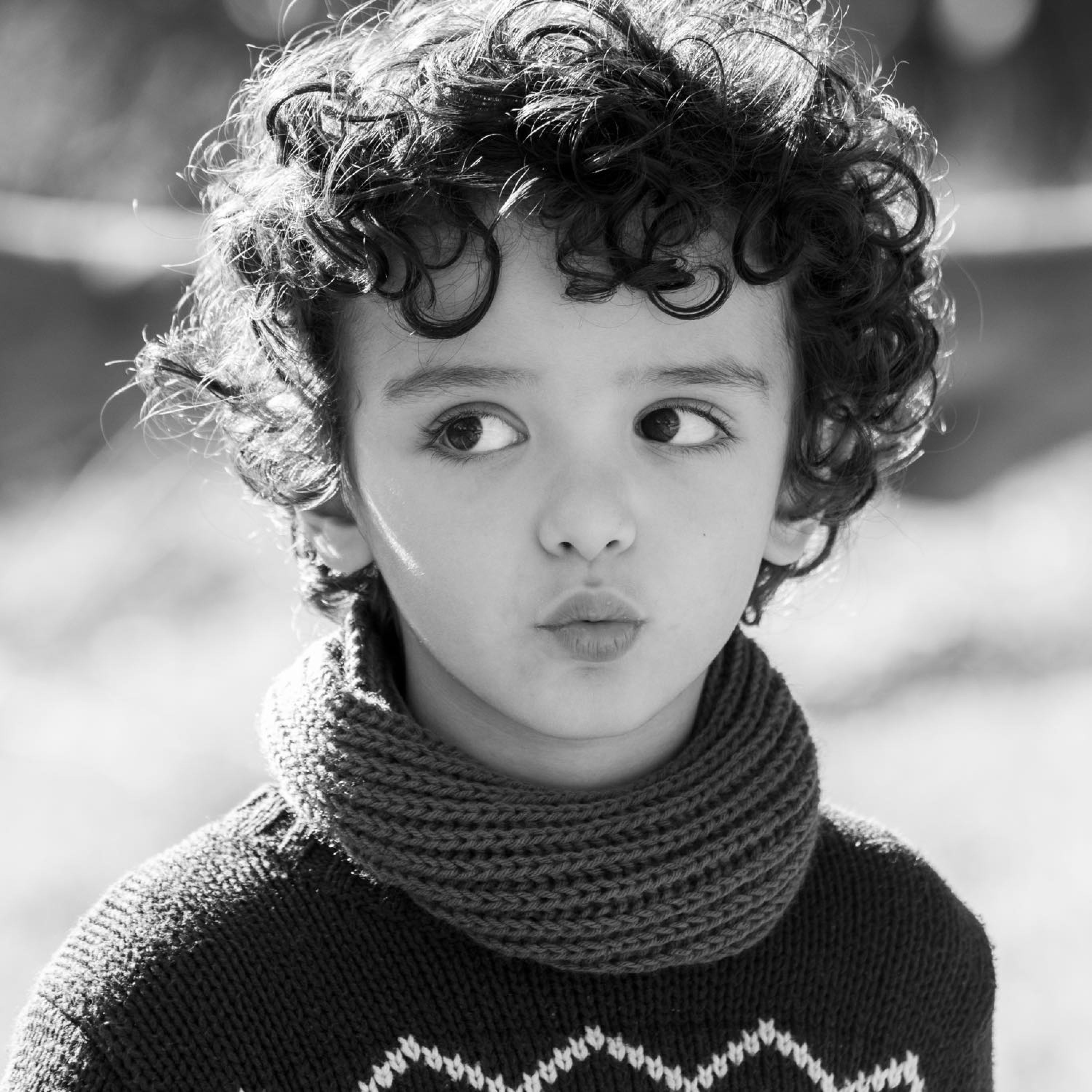 Black and white image of young boy with curly hair and big brown eyes.