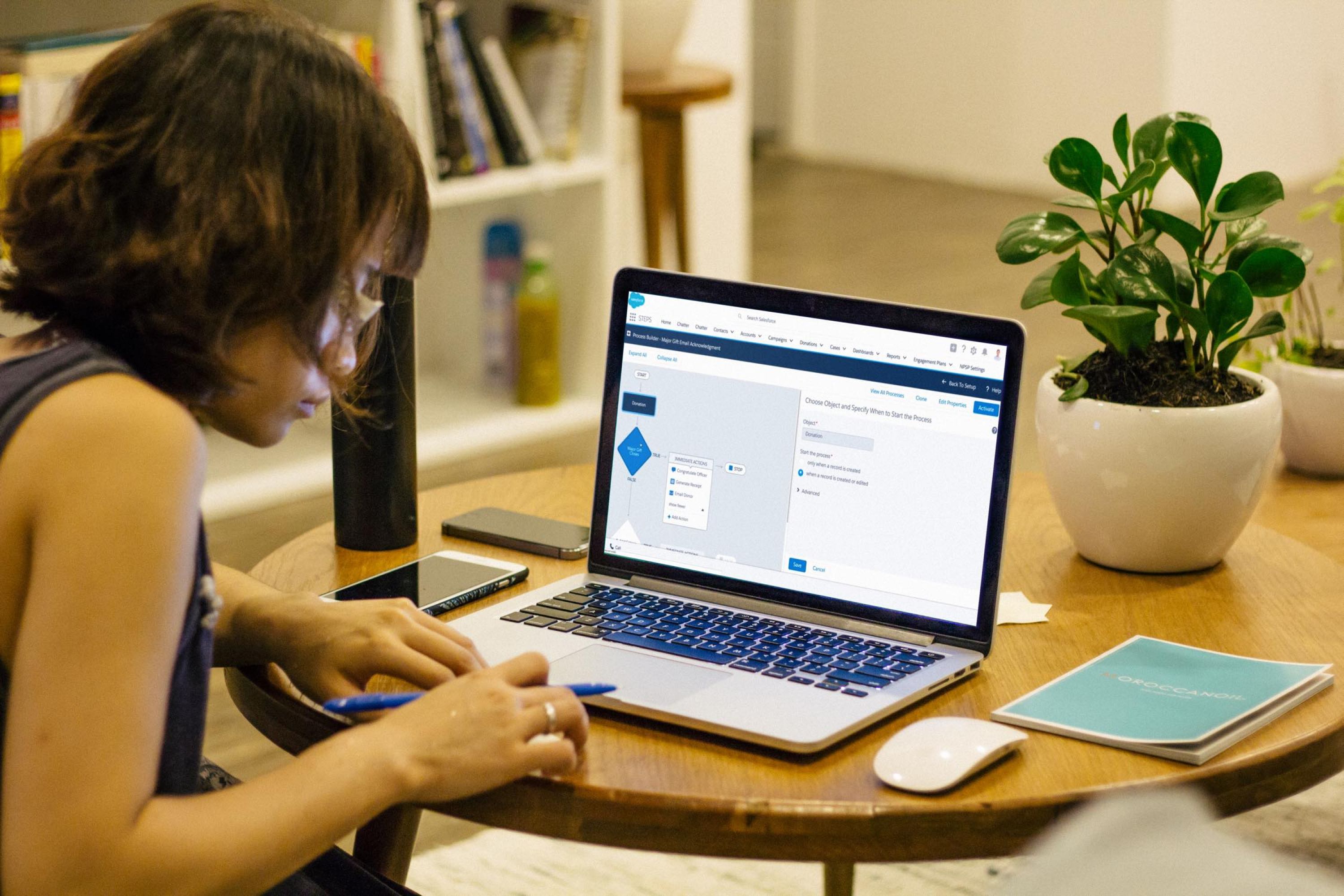 Woman at a table working on a laptop computer.