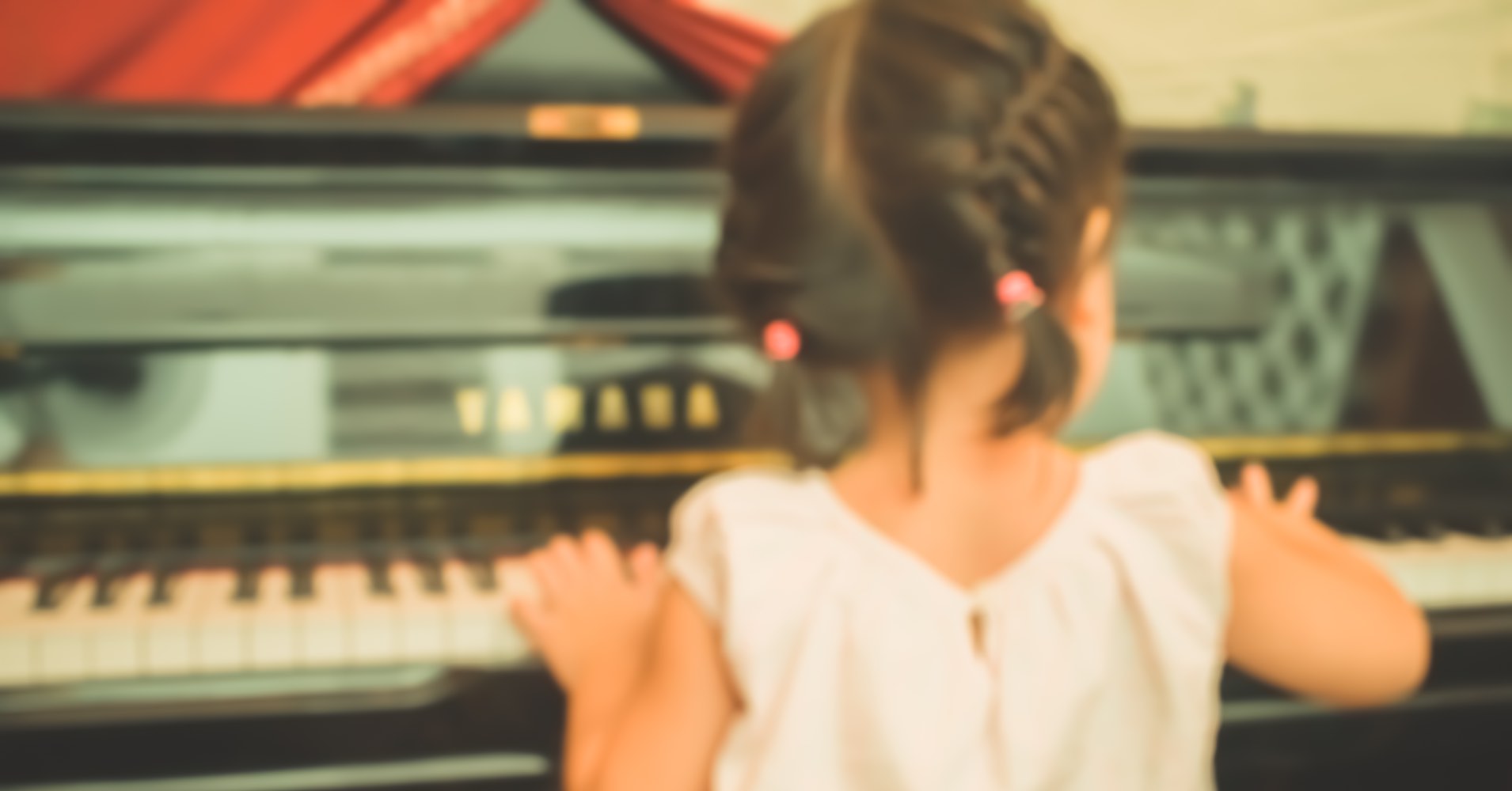 Little girl playing a Yamaha piano.