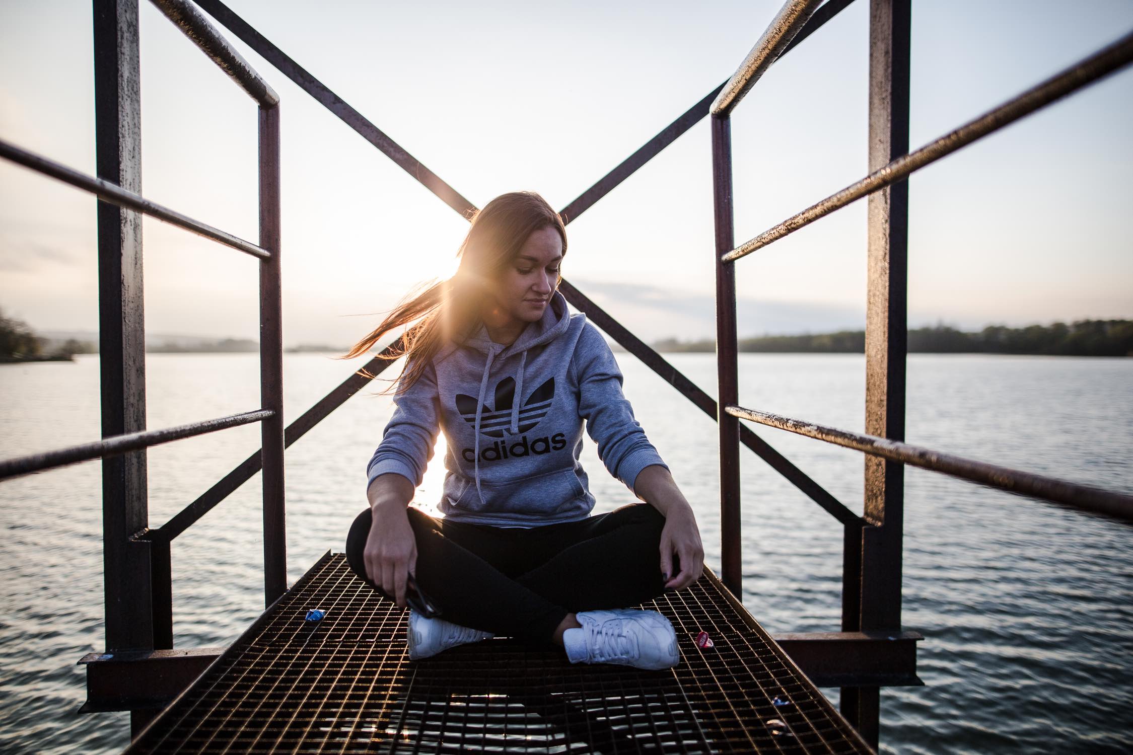 Image of girl sitting on a pier over the water.