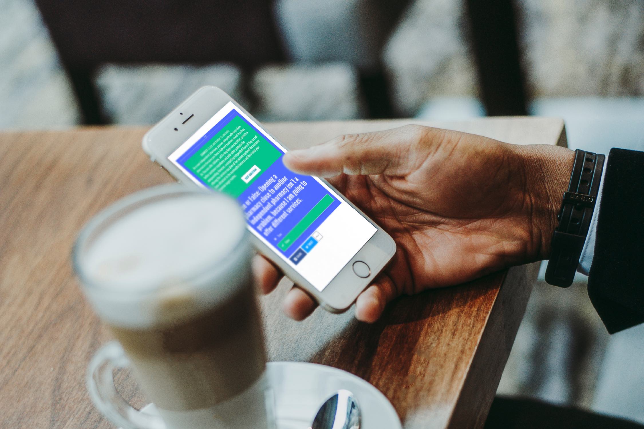 Image of hand holding a phone next to a coffee.