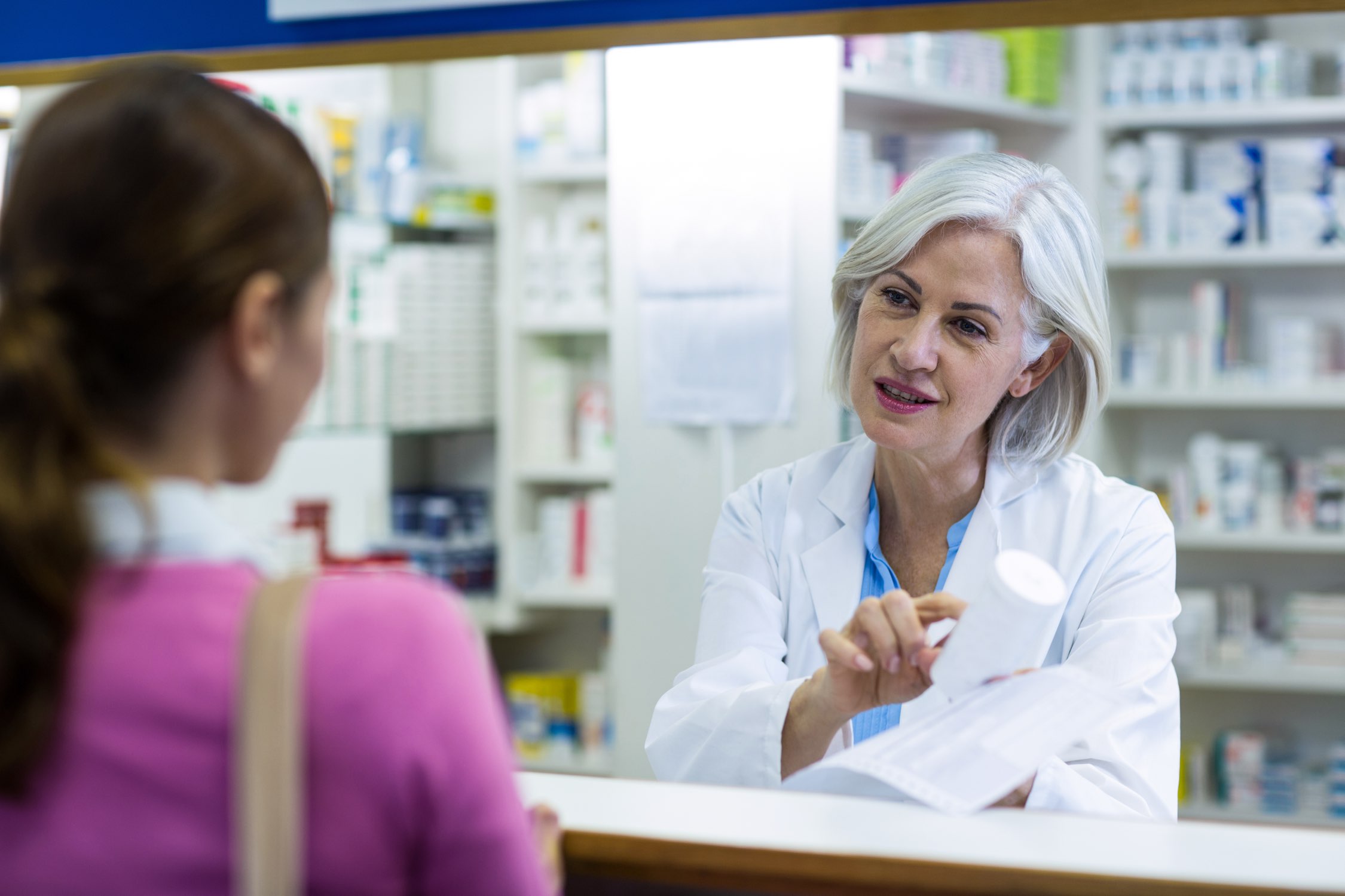 Image of pharmacists and a woman in a pharmacy.