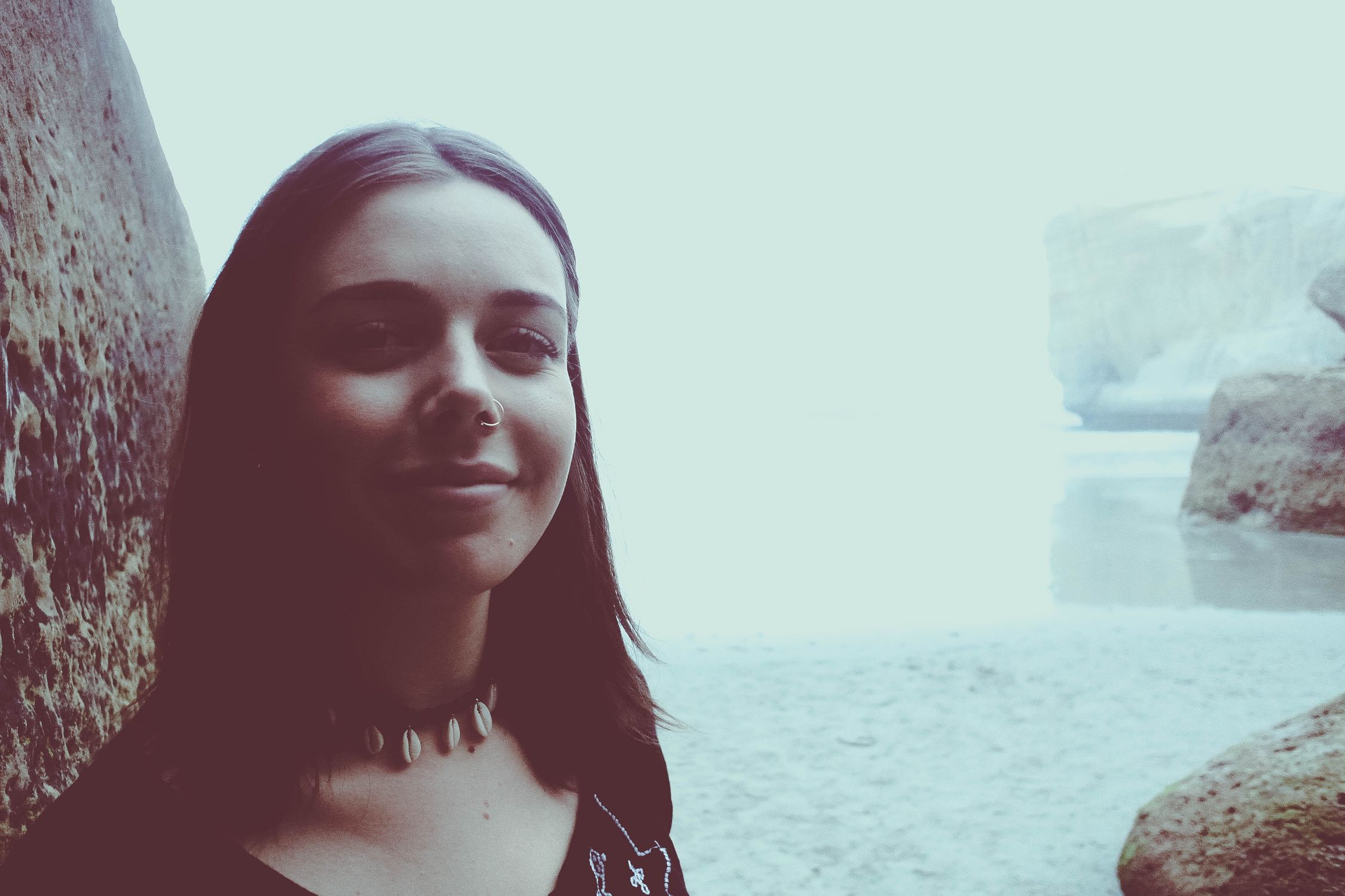 Image of girl by water and large rocks.