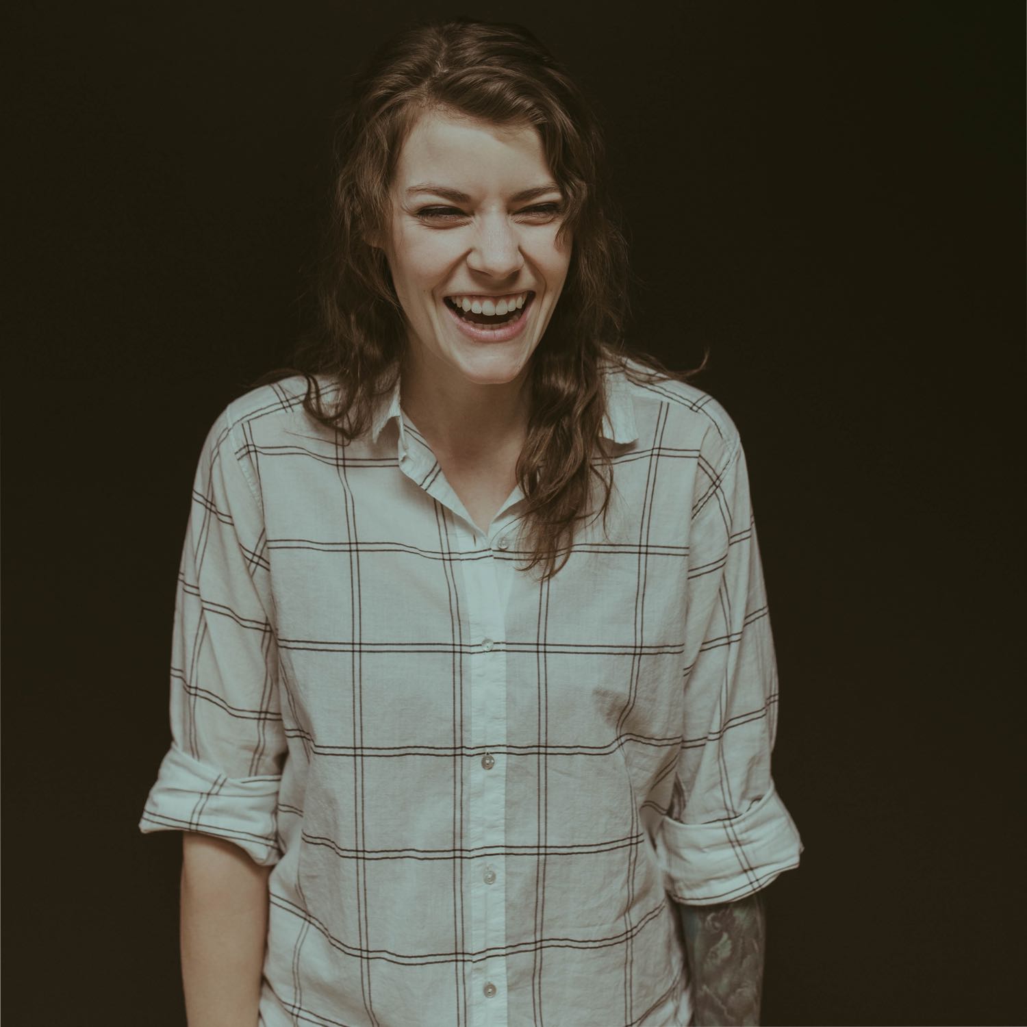 Image of woman wearing a plaid shirt and laughing.