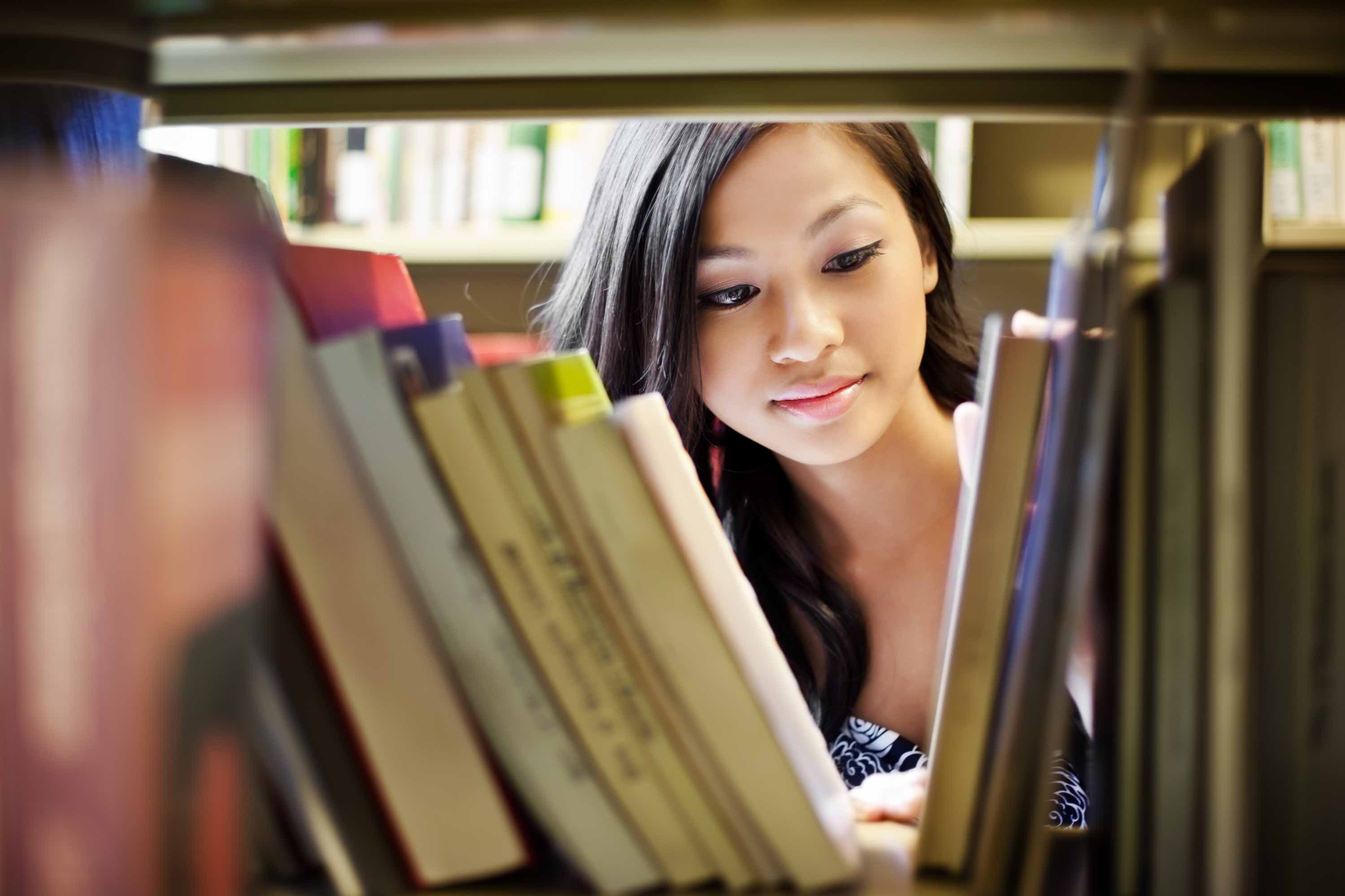 Image of girl shown through a library stack of books.