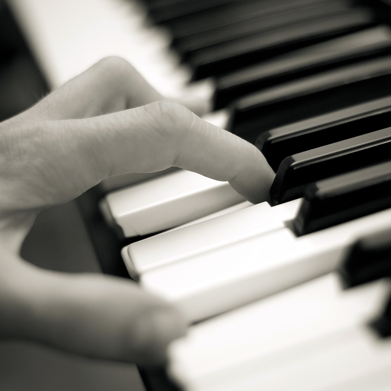 Hand playing keys on a piano.