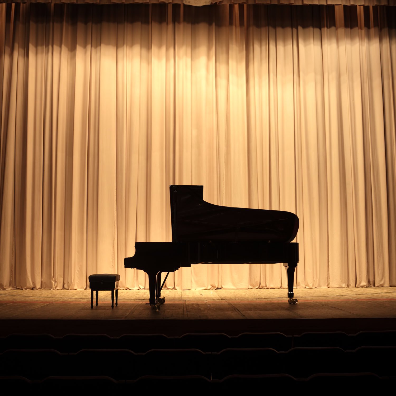 Image of a silhouette of a piano on a stage.