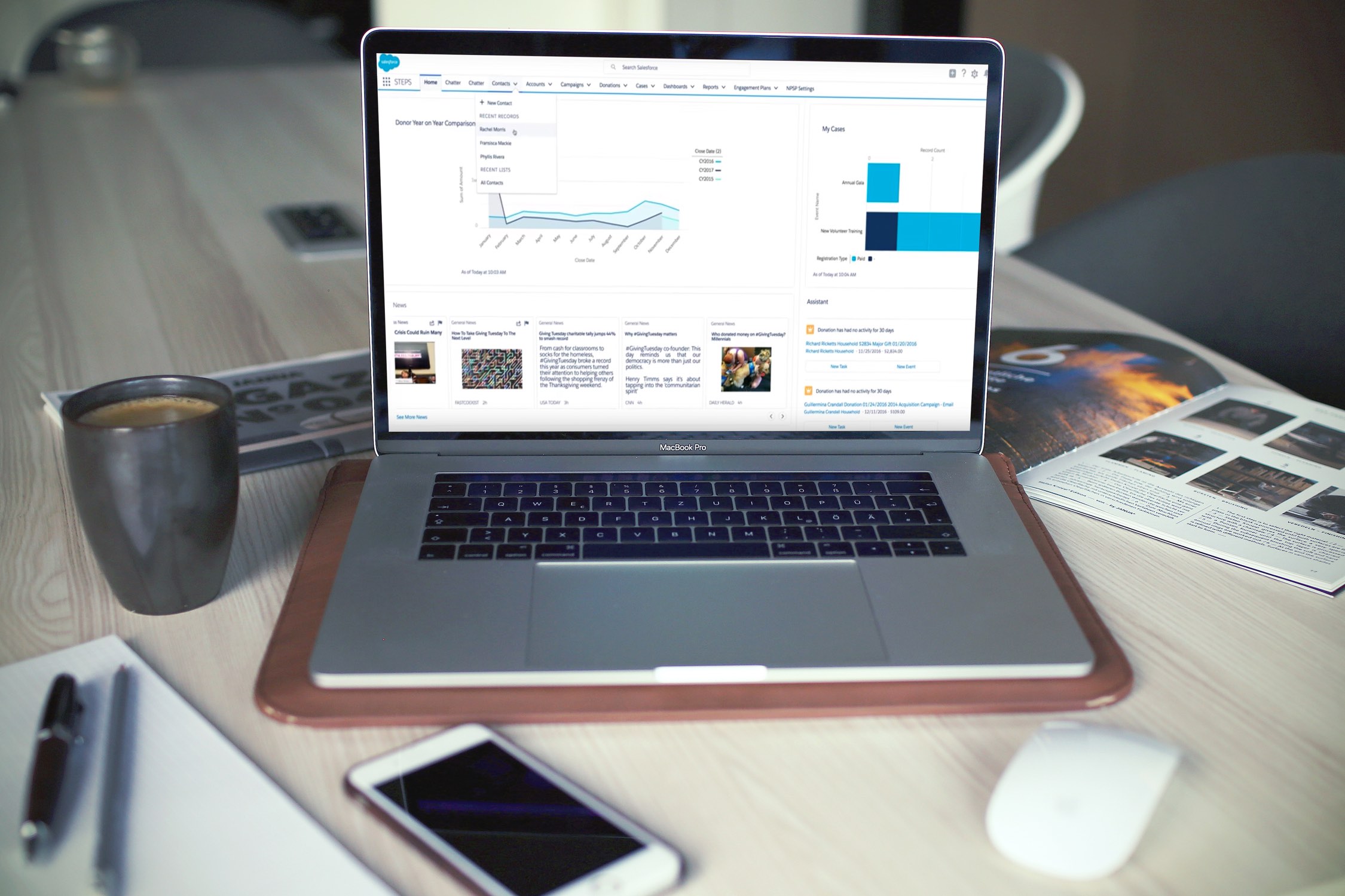 Image of a laptop on a desk alongside a coffee cup, pens and an iPhone.